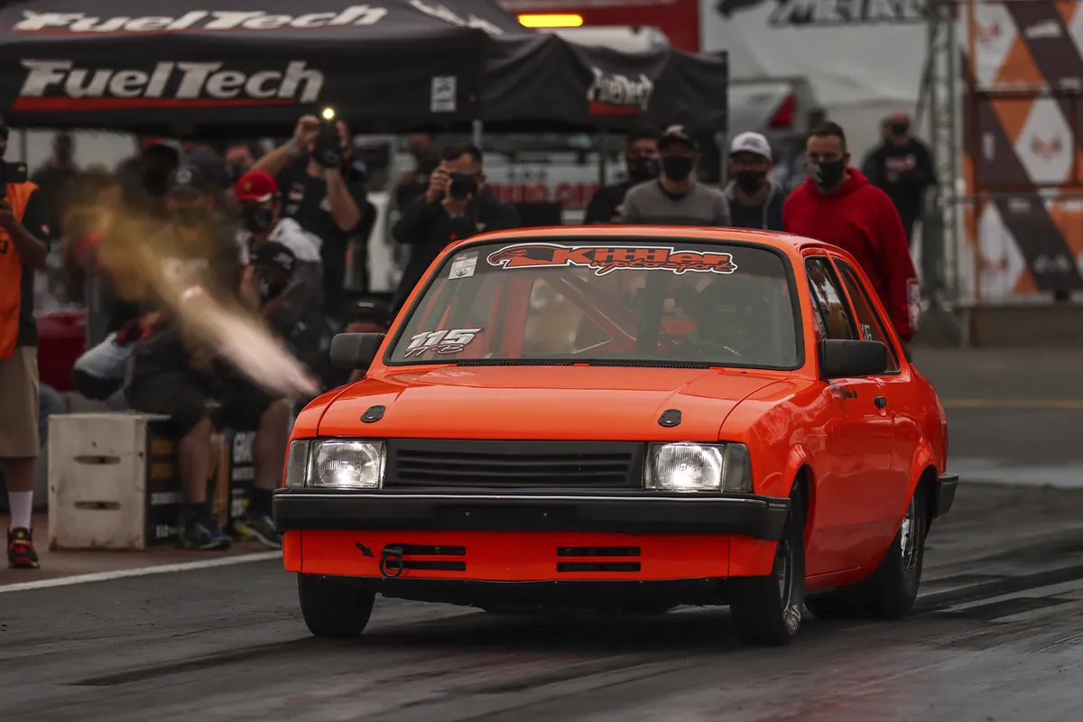 Chevette vermelho de arrancada na largada, com fumaça saindo do escapamento