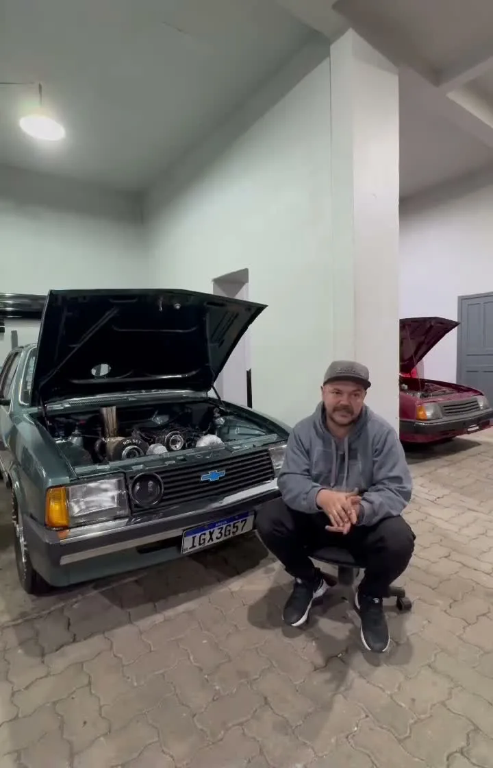 Juliano Rodrigues sentado ao lado do Chevette da Tech Racing na oficina
